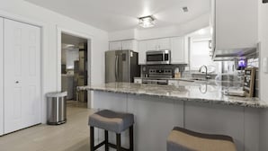 Una cocina moderna con armarios blancos, electrodomésticos de acero inoxidable y una encimera de granito.