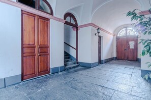Ein Flur mit einer Holztür, einer Treppe und einem großen Rundbogenfenster.