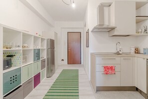 Una cucina moderna con mobili bianchi, un frigorifero in acciaio inossidabile e un tappeto a righe verdi.