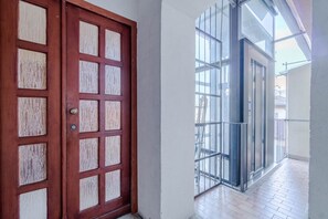 Eine Holztür mit Gittermuster, ein Balkon mit Metallgeländern und ein gefliester Boden.