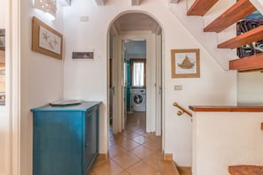 Ein Flur mit einer Waschmaschine, einem blauen Schrank und einer Treppe.