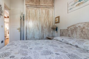 Ein Schlafzimmer mit einem Bett, einem Holzschrank, einem Nachttisch und einer Wandlampe.