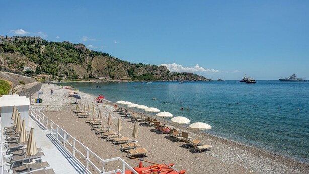 A beach with sun loungers, umbrellas, and a clear view of the sea. - GuestHost - Cozy 43 sqm ground floor apartment, perfect for three people (accessible via a few steps).The property enjoys a prime location, directly on the beach, with convenient access to the sea. The Taormina - Giardini train station is less than a 10- (Naxos)