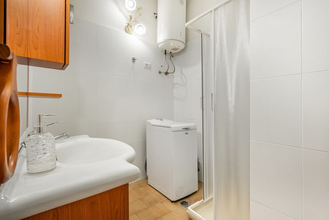 Une salle de bain avec un lavabo blanc, des toilettes, une douche et un meuble en bois.