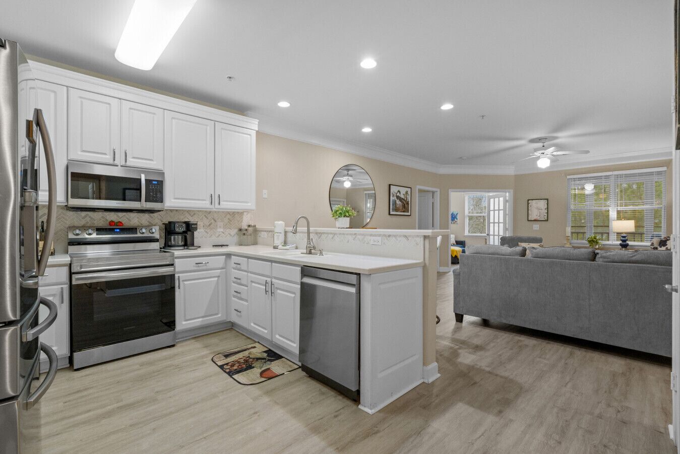 A modern kitchen with white cabinetry, stainless steel appliances, and a central island.