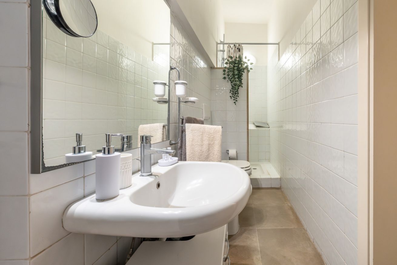 A bathroom with a white sink, mirror, and a shower area.