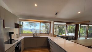 A modern kitchen with a large window, wooden flooring, and built-in appliances. - Valley View Escape: Wentworth Falls Blue Mountains (Wentworth Falls)