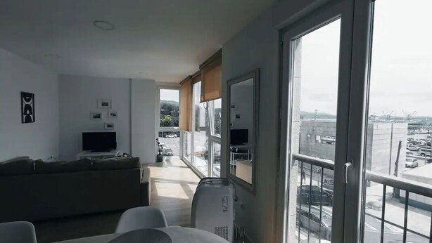 A modern living room with a sofa, dining table, and large windows offering a view of the city. - To María Bazarra's house. Sea views, elevator and air conditioning. (A Pobra do Caramiñal)