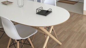 A modern kitchen with white cabinets, a refrigerator, and a dining area with a white table and chairs. - To María Bazarra's house. Sea views, elevator and air conditioning. (A Pobra do Caramiñal)