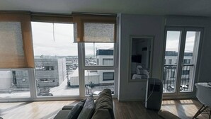 A modern living room with a large sofa, a dining table, and a view of a cityscape through large windows. - To María Bazarra's house. Sea views, elevator and air conditioning. (A Pobra do Caramiñal)