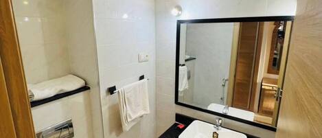 A modern bathroom with a white toilet, a black sink, and a large mirror.