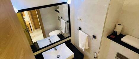 A modern bathroom with a black sink, white toilet, and a large mirror.