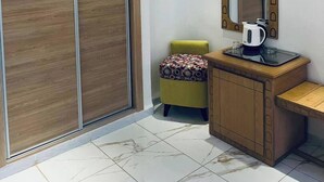 A modern bathroom with a wooden vanity, a mirror with a decorative frame, and an air conditioning unit above the mirror. - El Djanoub Hotel (Ghardaia)