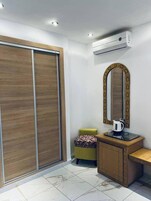 A modern bathroom with a wooden vanity, a mirror with a decorative frame, and an air conditioning unit above the mirror.