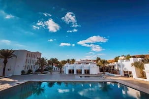 A swimming pool area with a clear blue sky and white buildings.