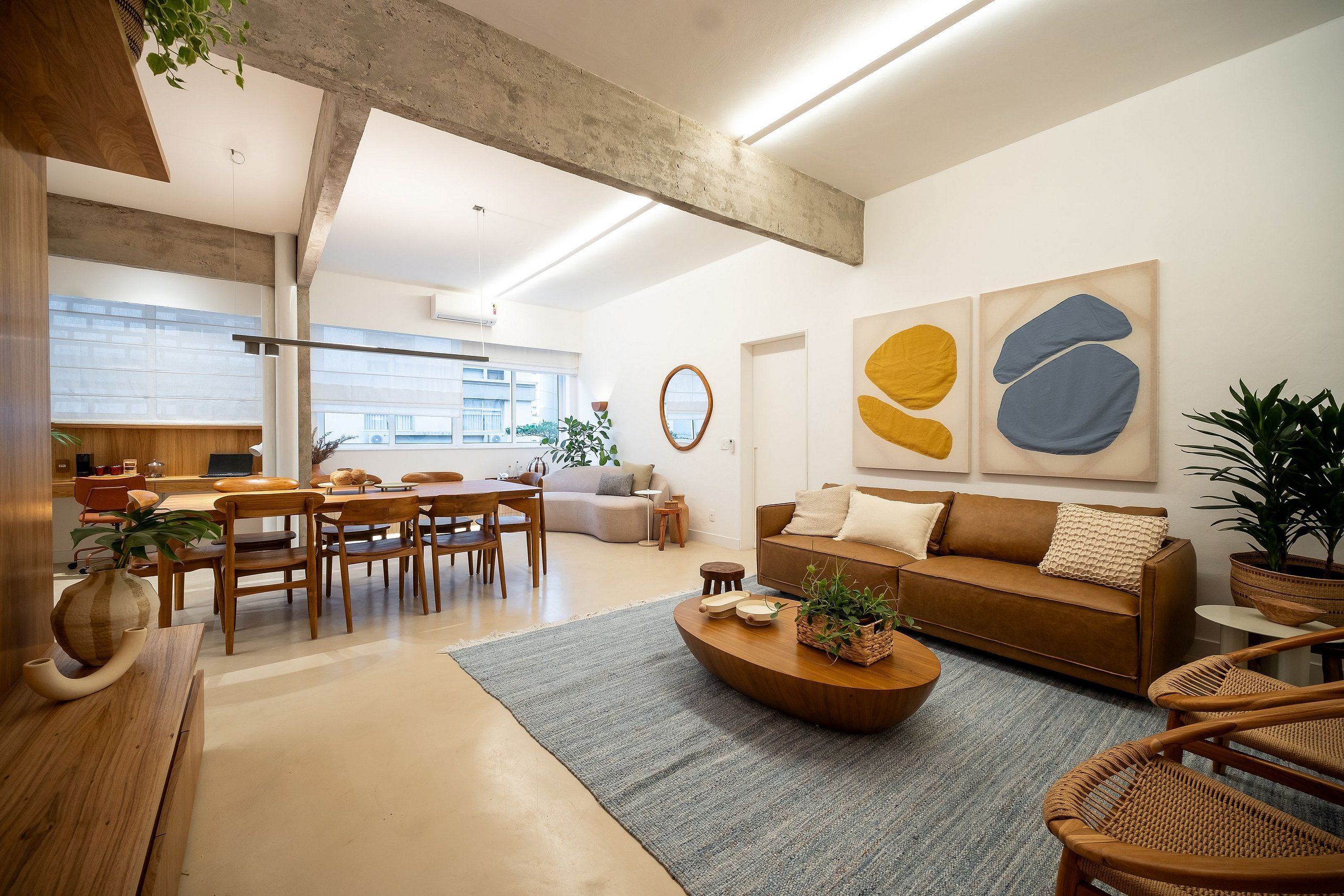 A modern living room with a sofa, coffee table, and chairs, a dining area with a table and chairs, and a kitchen in the background.