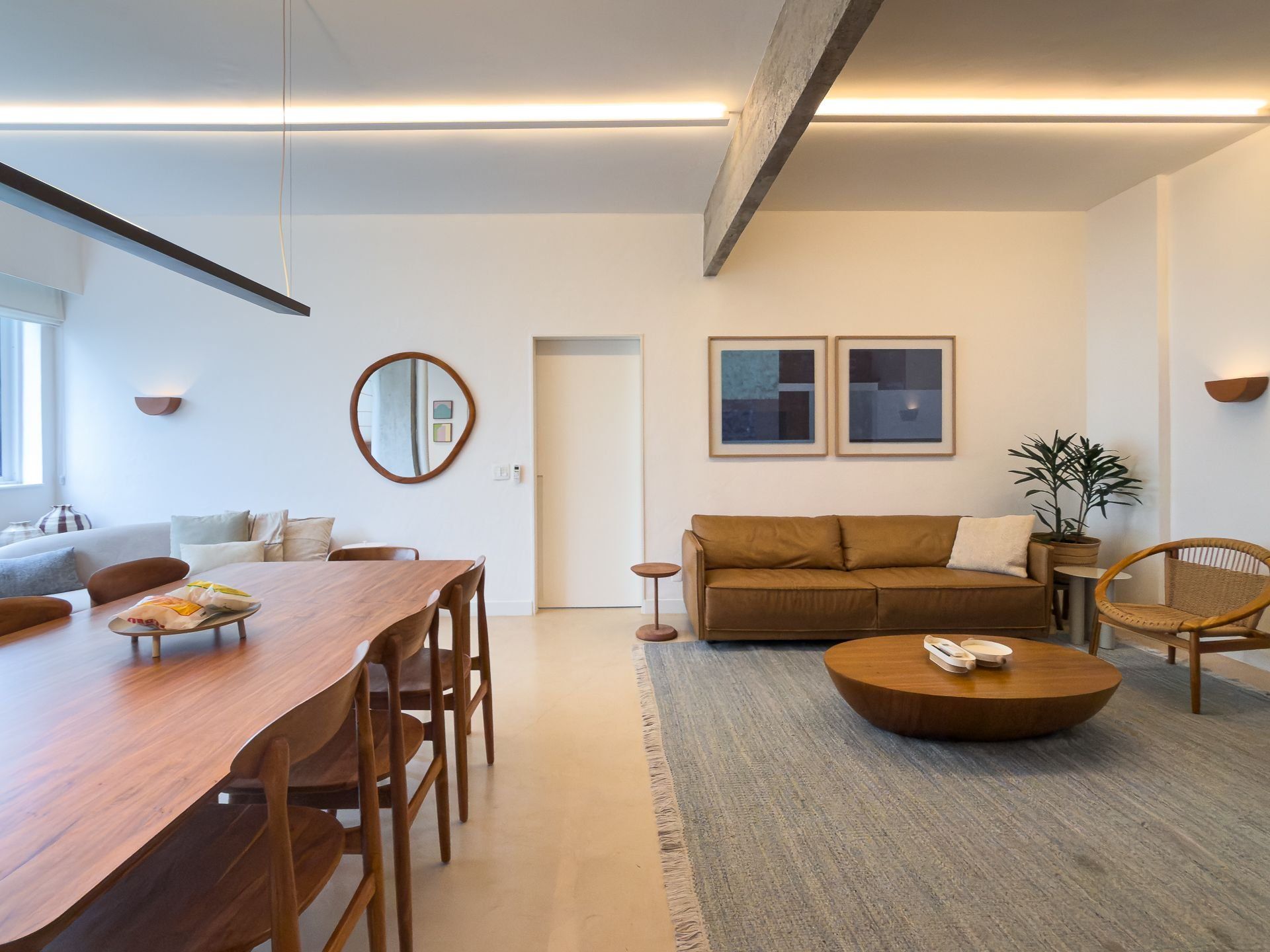 A modern living room with a wooden dining table, a brown sofa, and a round coffee table.