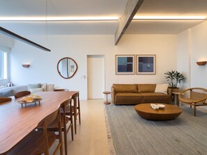 Een moderne woonkamer met een houten eettafel, een bruine bank en een ronde salontafel.