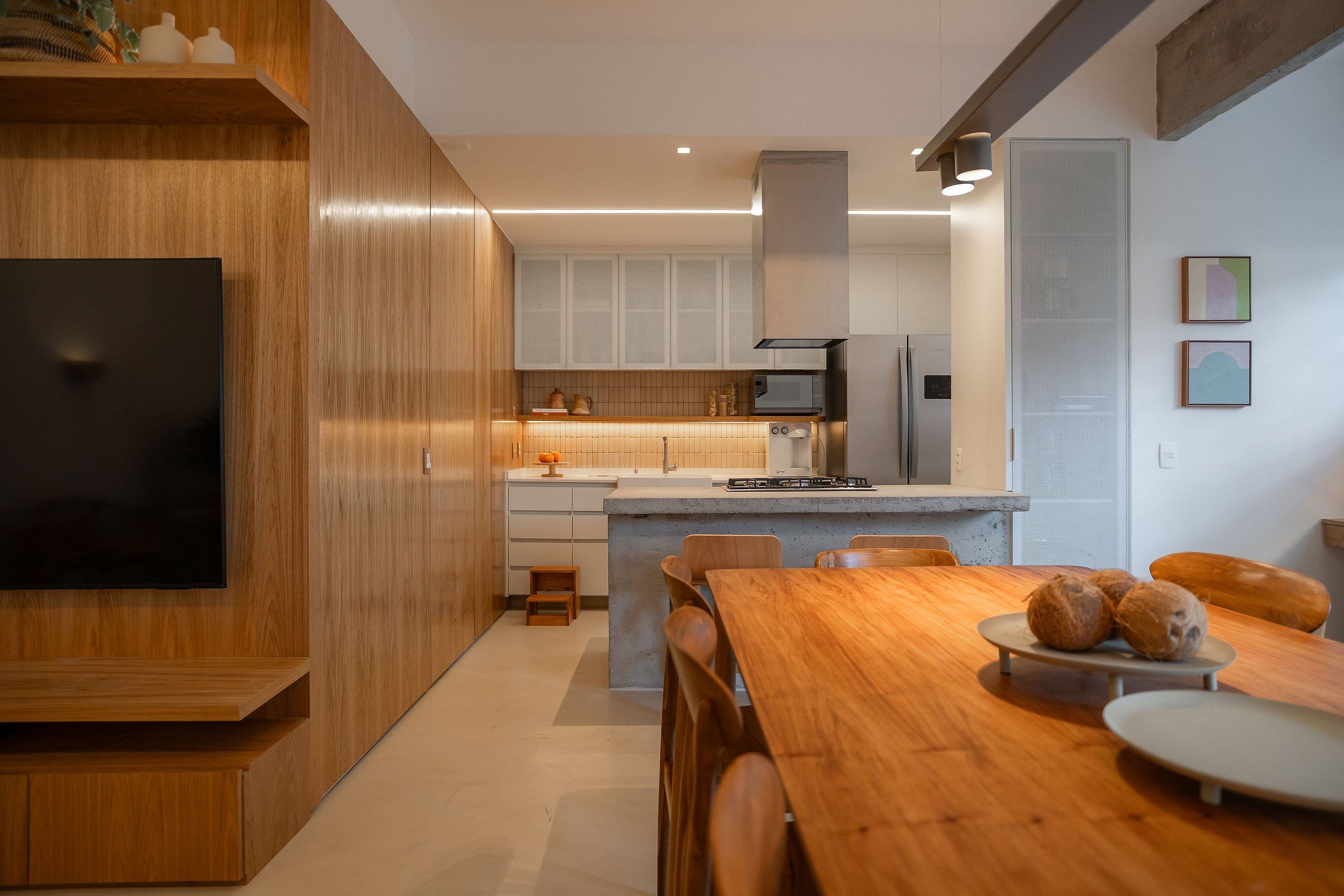 A modern kitchen with wooden cabinetry, a central island, and a dining area with a wooden table and chairs.