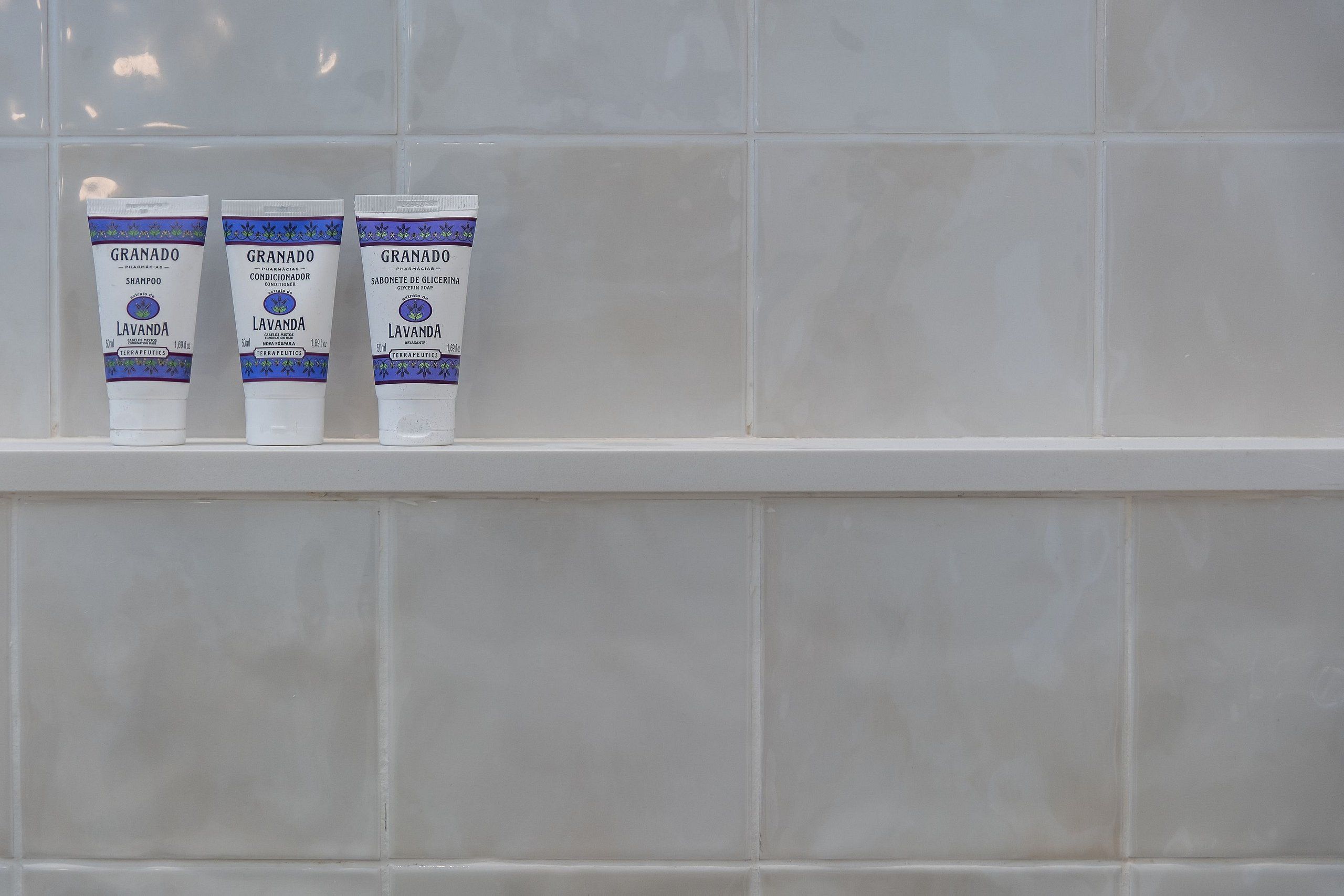 Three tubes of Granado shampoo and conditioner on a white shelf against a tiled wall.