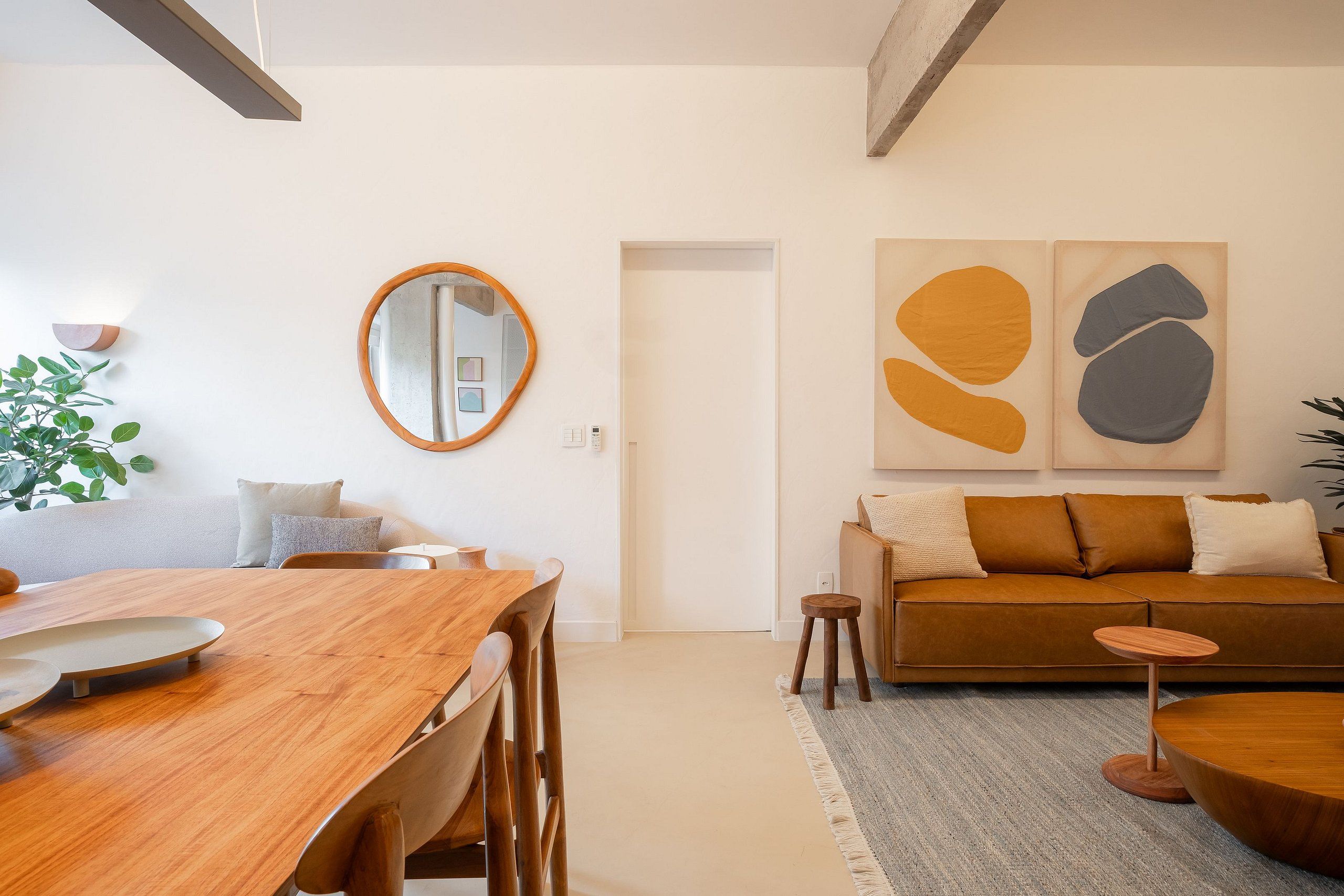 Ein modernes Wohnzimmer mit einem Holzesstisch, einer Couch und abstrakter Wandkunst.