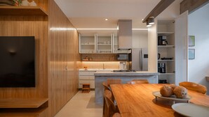 Une cuisine moderne avec des meubles en bois, un îlot central intégré et un coin repas comprenant une table et des chaises en bois.