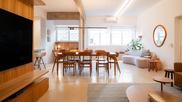 Un salon moderne doté d’un téléviseur à écran plat, d’une table à manger en bois et de chaises. On y trouve également un canapé et une table basse.