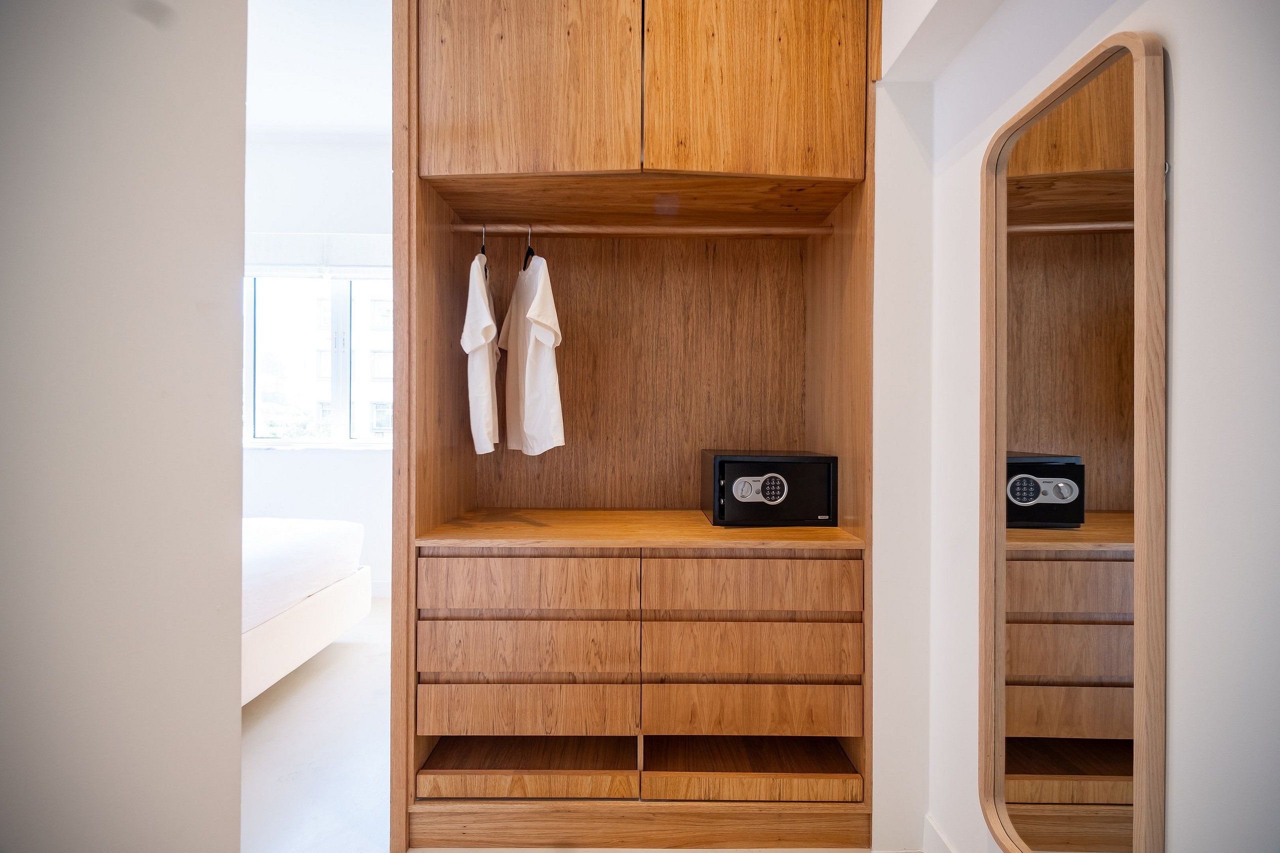 A wooden wardrobe with multiple compartments, a mirror, and a radio.