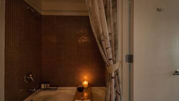 A bathroom with a bathtub, a shower curtain, and a candle on a tray.