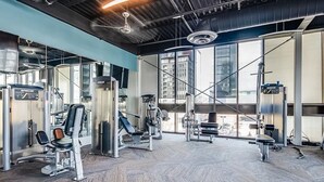 Une salle de sport équipée de matériel d’exercice, dotée de grandes fenêtres et d’un plafond haut.