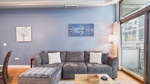 Un salon moderne avec un canapé d’angle, une table basse et des œuvres d’art accrochées aux murs.