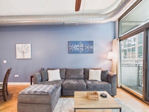 A modern living room with a sectional sofa, a coffee table, and artwork on the walls.