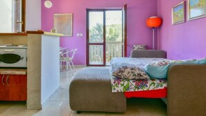 Une chambre à coucher avec un lit, un bureau et une chaise. Il y a une fenêtre qui donne sur un paysage verdoyant.