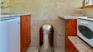 Une petite cuisine équipée d’un évier, d’une cuisinière et d’une poubelle.