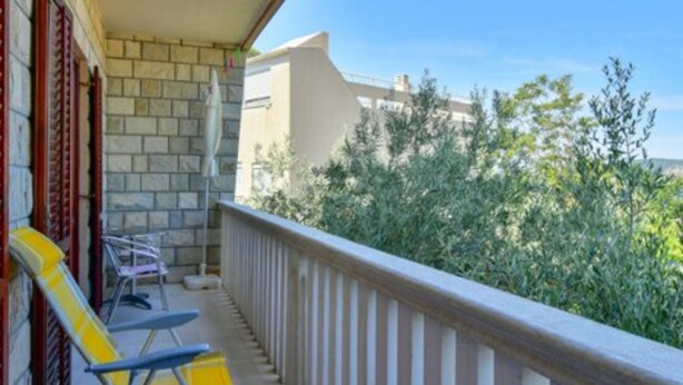 Un balcon avec une balustrade, une chaise jaune et une chaise bleue.