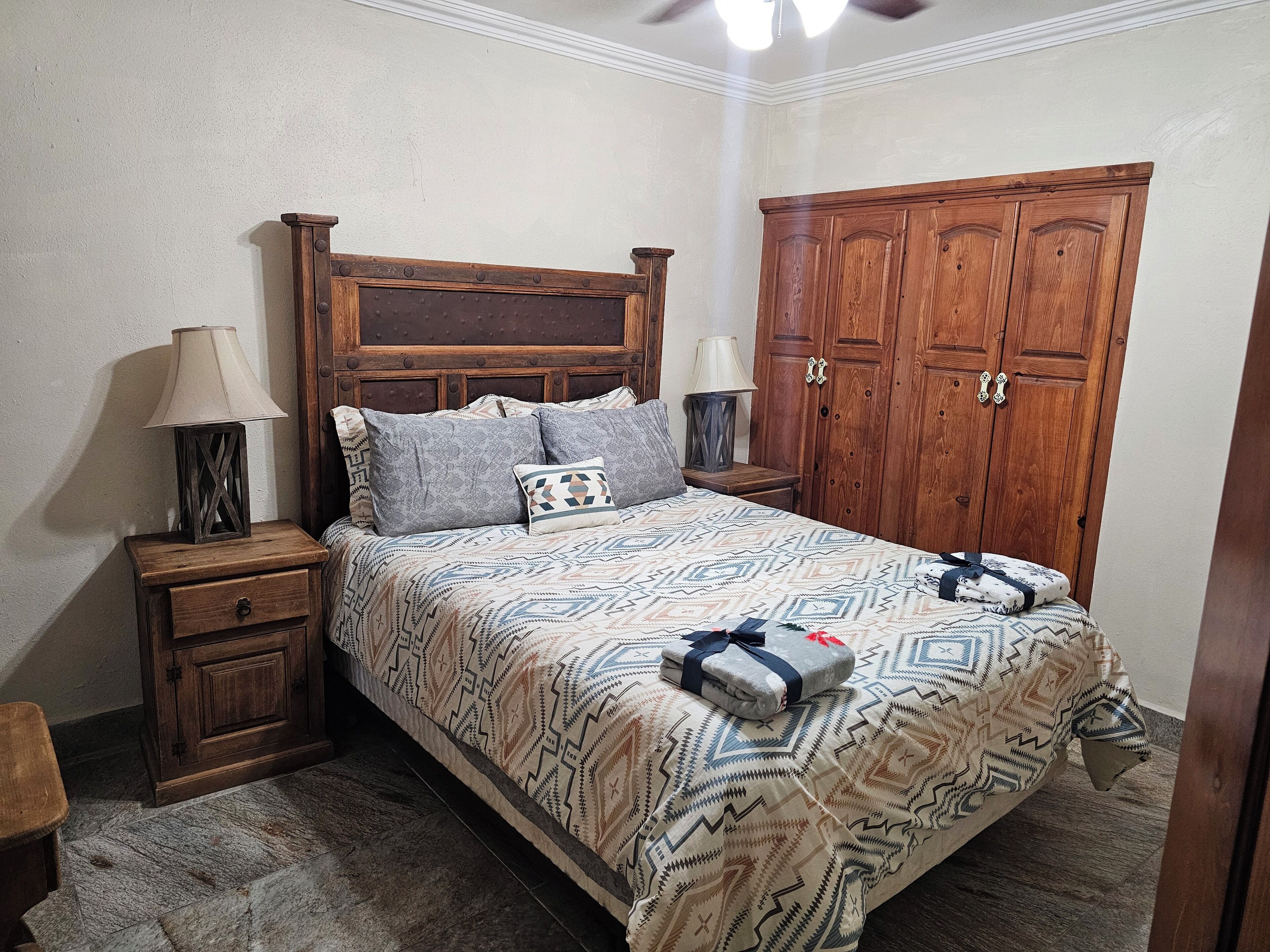 A bedroom with a wooden bed, two nightstands, a wardrobe, and a ceiling fan.