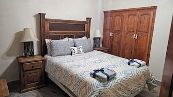 A bedroom with a wooden bed, two nightstands, a wardrobe, and a ceiling fan.