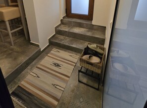 Eine Treppe mit einem gemusterten Teppich und einem Korbkörbchen mit Hausschuhen.