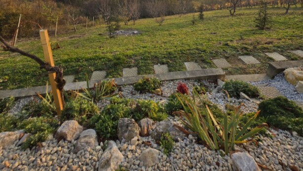 A garden with a stone pathway, various plants, and a wooden fence. - Villa Bella Vista - One Bedroom apartment with Balcony and View (Ivanec)