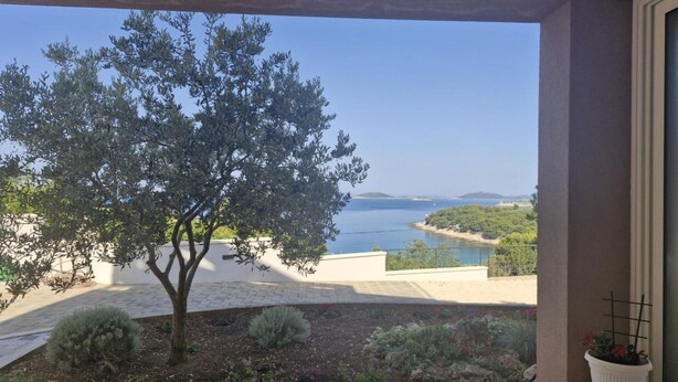 A terrace with a view of the sea, a tree, and a table with chairs. - Apartment Slanica Beach Escape - One Bedroom Apartment With Terrace And Sea View (Murter)