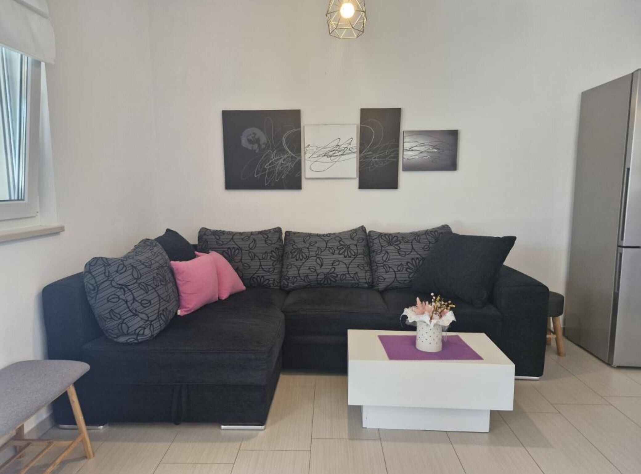 Ein modernes Wohnzimmer mit einer Eckcouch, einem weißen Couchtisch und abstrakter Wandkunst.