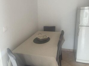 A small, clean room with a single dining table, a chair, and a white refrigerator. - Family house Kurtin by Brankica - Two bedroom apartment (Ugljan)