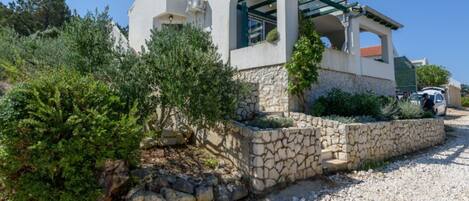 A modern house with a stone retaining wall, a covered porch, and a gravel driveway.