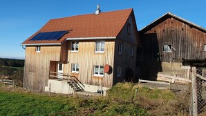 A wooden house with a red-tiled roof, solar panels, and a satellite dish. - Vacation home in the heart of the Allg äu in Heimenkich (Heimenkirch)