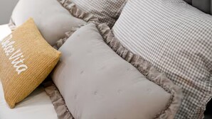 A bed with a grey upholstered headboard, a beige pillow with embroidered text, and a grey pillow with a checkered pattern. - Zadar Apartment Sweet Life - Studio Apartment with Balcony (Zadar)