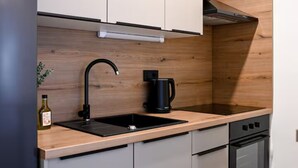 A modern kitchen with a black faucet, a coffee maker, and a bottle of olive oil on the counter. - Zadar Apartment Sweet Life - Studio Apartment with Balcony (Zadar)