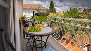 Een balkon met een gedekte tafel voor een maaltijd, inclusief druiven, brood en een fles wijn.
