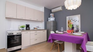Een moderne keuken met een eethoek, voorzien van een inbouwoven, een magnetron en een koelkast.