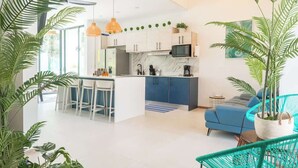 Eine moderne Küche mit weißen Schränken, einer blauen Arbeitsplatte und einem Essbereich mit weißen Stühlen.