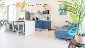 Eine moderne Küche mit weißen Schränken, einer zentralen Kochinsel mit Barhocker, einer Mikrowelle und einer Kaffeemaschine.